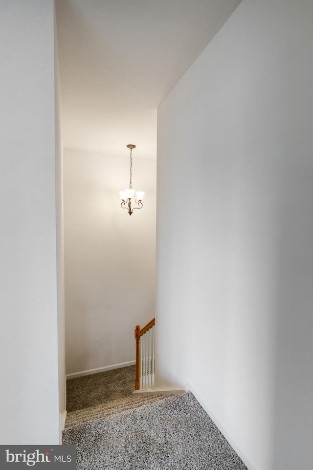 staircase featuring carpet flooring, baseboards, and an inviting chandelier