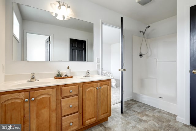 bathroom featuring double vanity, walk in shower, and a sink