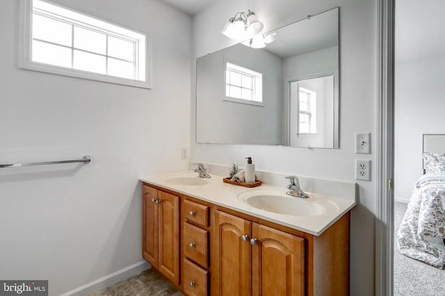 bathroom with a sink, baseboards, an inviting chandelier, and double vanity