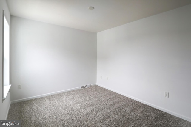 empty room featuring visible vents, baseboards, and carpet flooring