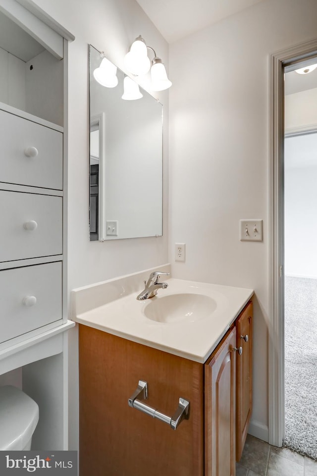 half bath featuring vanity, toilet, and tile patterned flooring