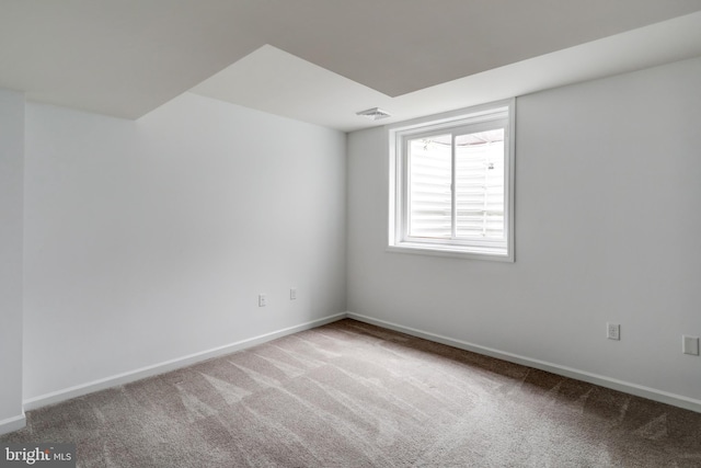 carpeted spare room with visible vents and baseboards