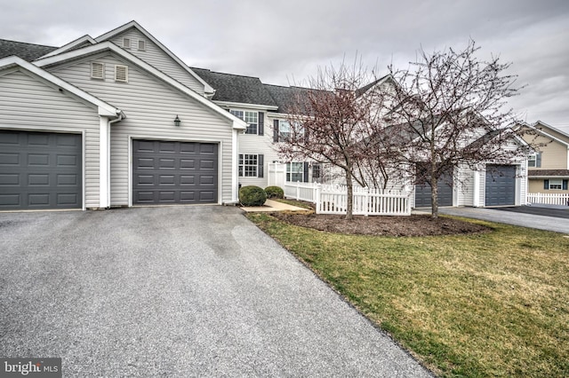 view of front of home with a garage, driveway, and fence