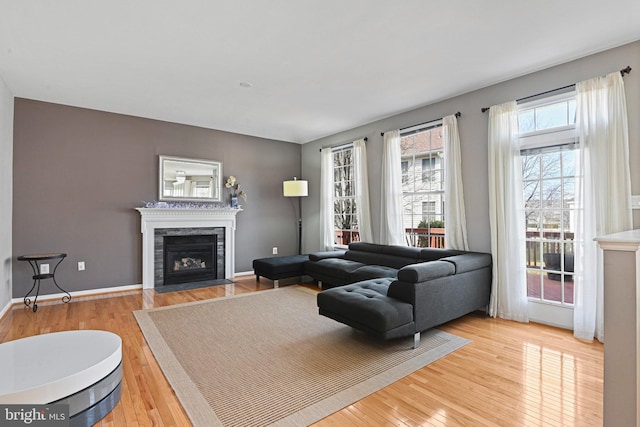 living room featuring baseboards, light wood-type flooring, and a high end fireplace