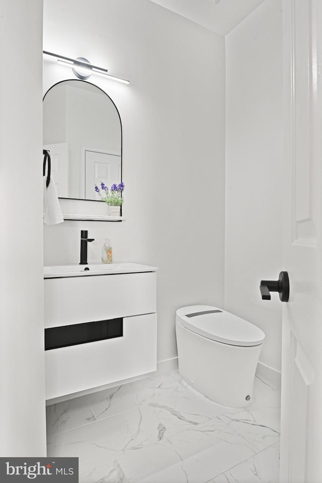 bathroom with baseboards, toilet, marble finish floor, and vanity