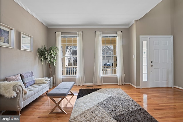 foyer with ornamental molding, baseboards, and wood finished floors