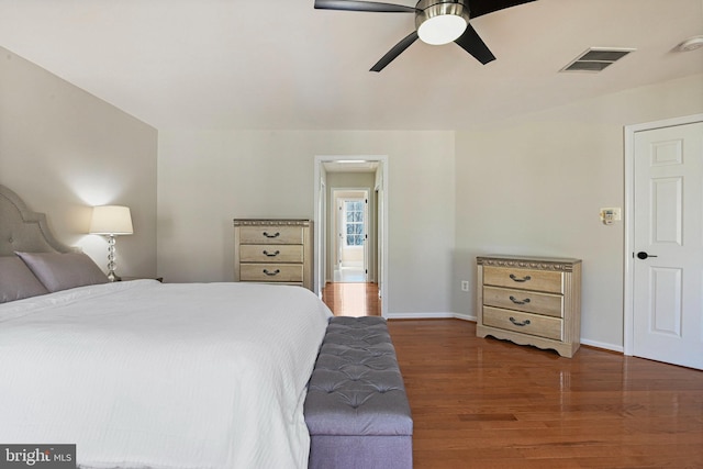 bedroom with ceiling fan, visible vents, baseboards, and wood finished floors