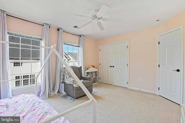 carpeted bedroom with visible vents, baseboards, a closet, and a ceiling fan