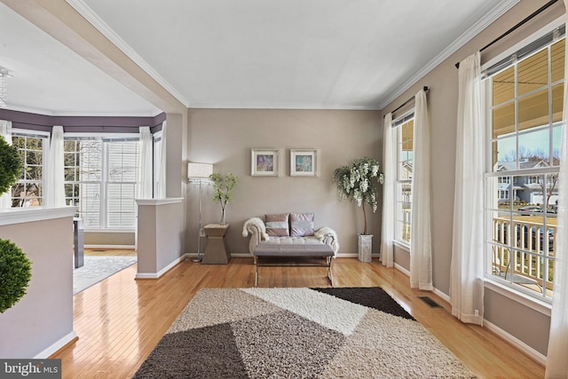 living area featuring visible vents, baseboards, wood finished floors, and ornamental molding