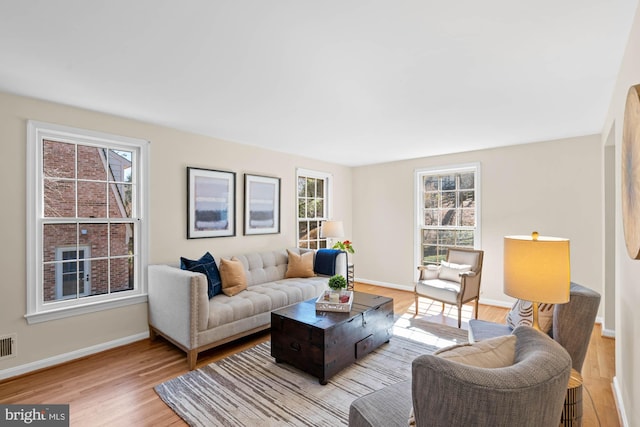 living area with light wood-style flooring, visible vents, and baseboards