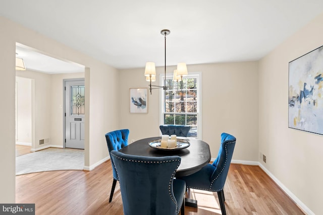 dining space with an inviting chandelier, baseboards, light wood-type flooring, and visible vents