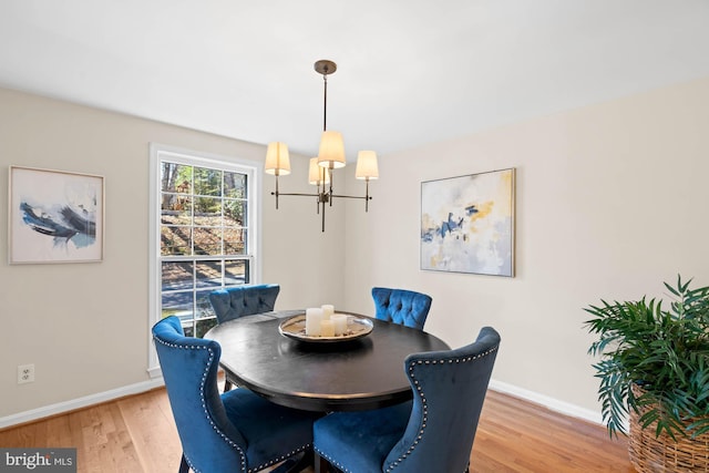 dining area featuring light wood-style floors, baseboards, and a chandelier