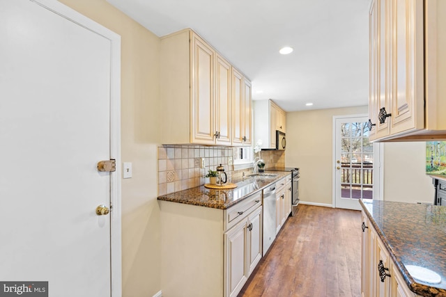 kitchen featuring cream cabinetry, dark stone countertops, tasteful backsplash, light wood-style floors, and baseboards