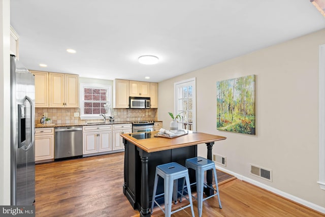 kitchen featuring a kitchen breakfast bar, visible vents, backsplash, and stainless steel appliances