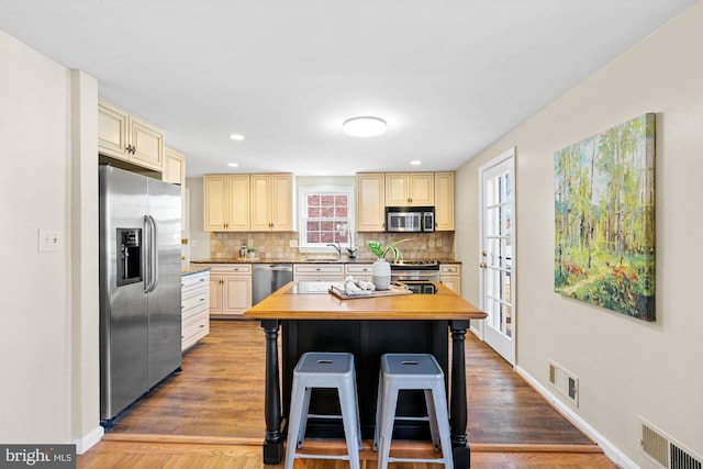 kitchen with cream cabinets, tasteful backsplash, visible vents, and appliances with stainless steel finishes