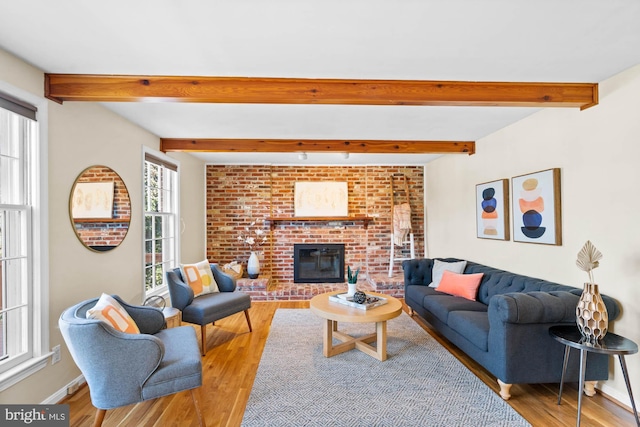 living area featuring wood finished floors, a fireplace, baseboards, and beam ceiling