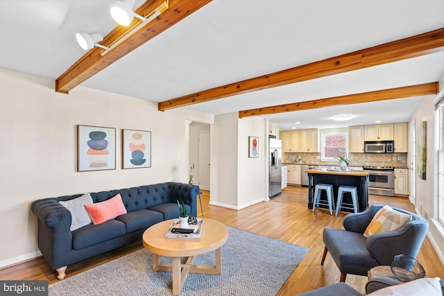 living area with light wood-type flooring, baseboards, and beam ceiling