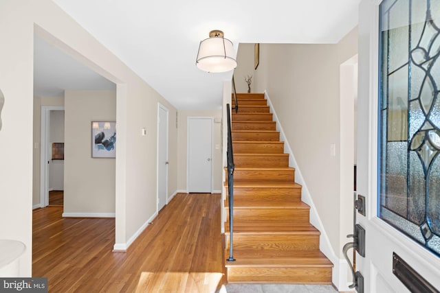 entrance foyer featuring stairway, light wood-type flooring, and baseboards