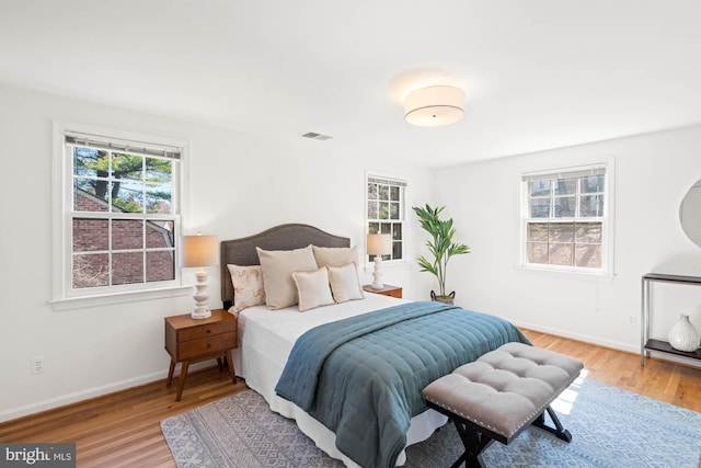 bedroom with light wood-style flooring, visible vents, and baseboards