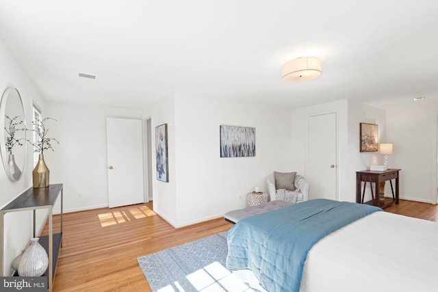 bedroom with light wood-type flooring, baseboards, and visible vents