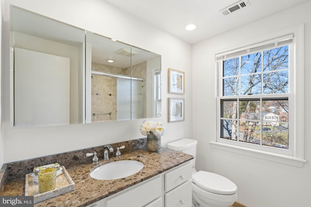 full bath featuring vanity, toilet, visible vents, and a stall shower