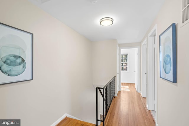 hall with baseboards, an upstairs landing, and light wood finished floors