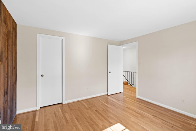 unfurnished bedroom featuring light wood-type flooring, baseboards, and a closet