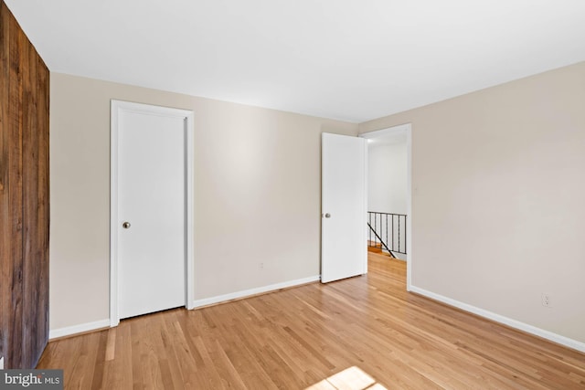 unfurnished bedroom with a closet, baseboards, and light wood finished floors