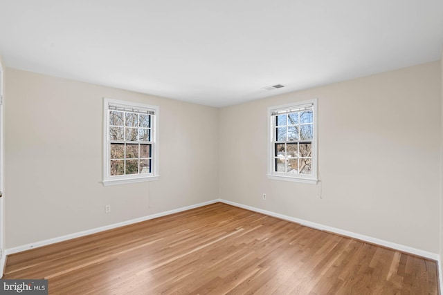 empty room with visible vents, baseboards, and wood finished floors