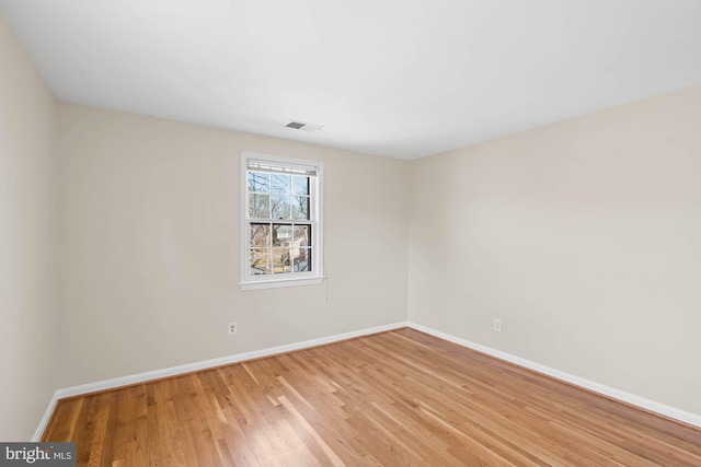 unfurnished room featuring light wood-style floors, visible vents, and baseboards