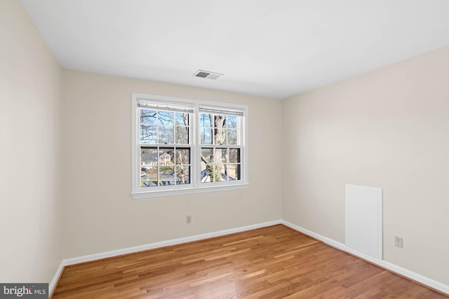 spare room with visible vents, baseboards, and wood finished floors