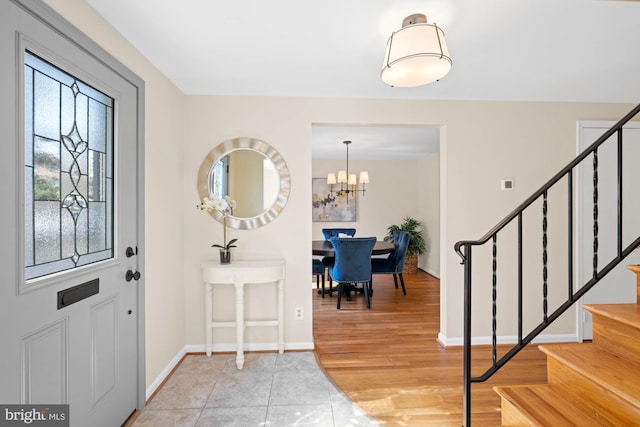 entryway with an inviting chandelier, stairway, light wood-style floors, and baseboards