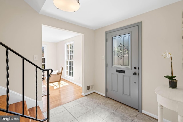 foyer entrance featuring stairway, light tile patterned floors, baseboards, and visible vents