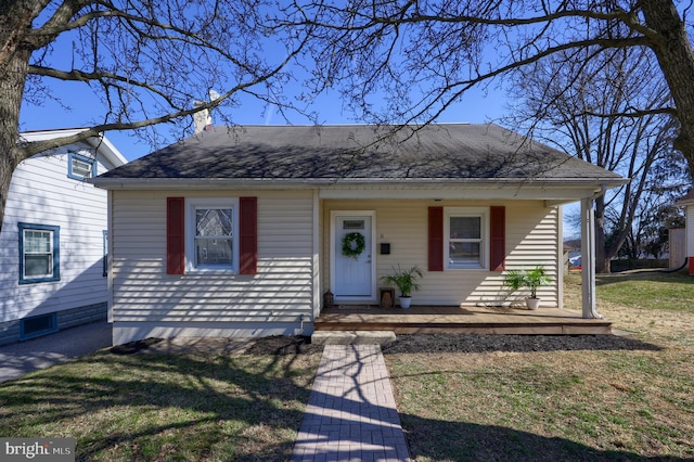 bungalow featuring covered porch and a front lawn