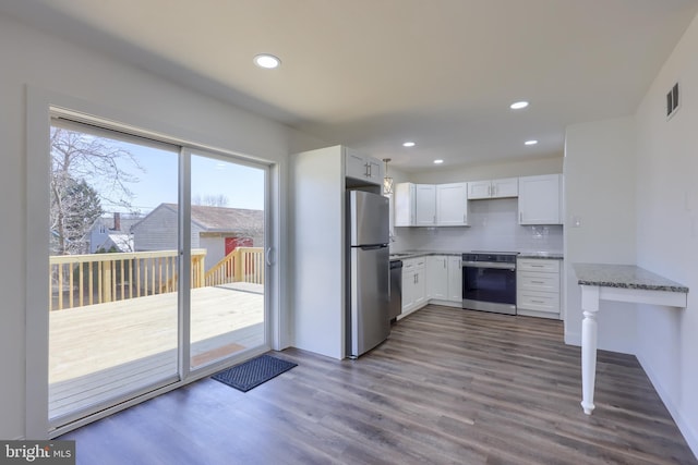 kitchen featuring dark wood-type flooring, decorative backsplash, appliances with stainless steel finishes, white cabinets, and stone countertops