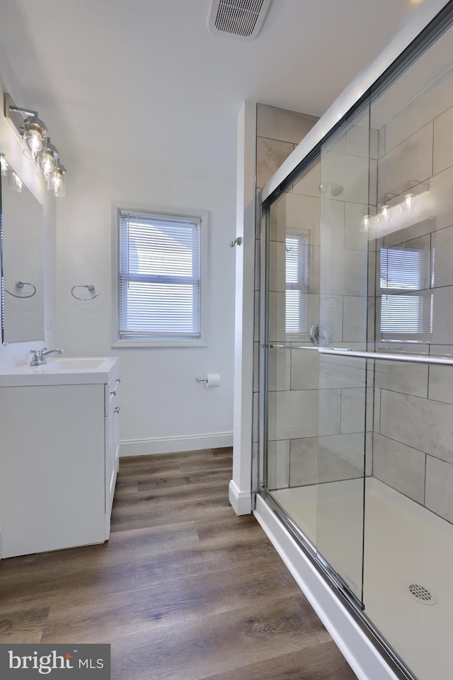 bathroom with vanity, a shower stall, wood finished floors, and visible vents