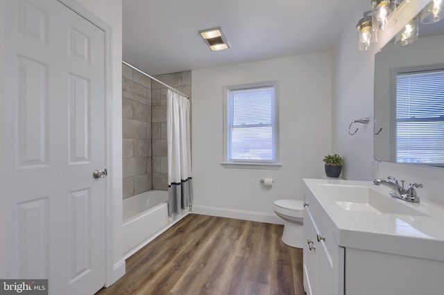 bathroom with baseboards, toilet, shower / tub combo, wood finished floors, and vanity