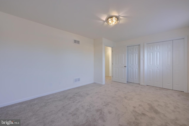 unfurnished bedroom with visible vents, carpet floors, two closets, and baseboards