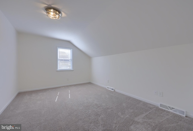 additional living space featuring vaulted ceiling, carpet flooring, baseboards, and visible vents