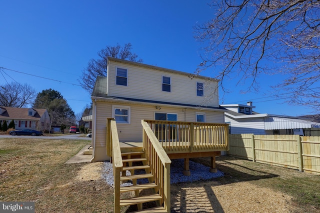 rear view of property featuring a deck, stairway, and fence