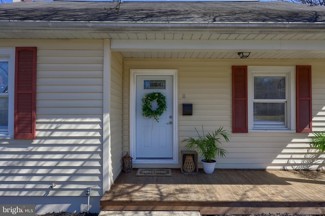 doorway to property with roof with shingles