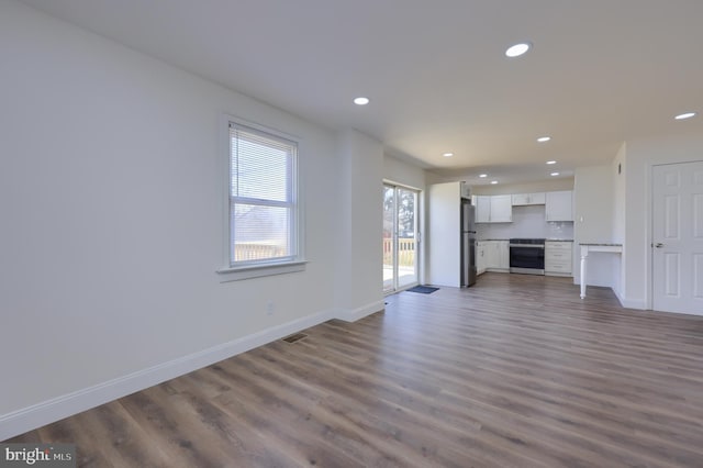 unfurnished living room with dark wood finished floors, visible vents, recessed lighting, and baseboards