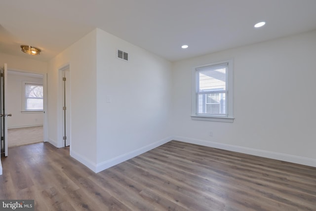 empty room with dark wood finished floors, visible vents, recessed lighting, and baseboards