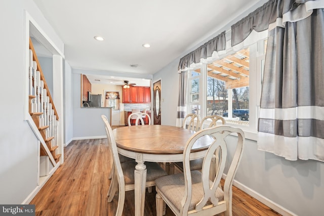 dining room featuring light wood-style flooring, a ceiling fan, recessed lighting, baseboards, and stairs