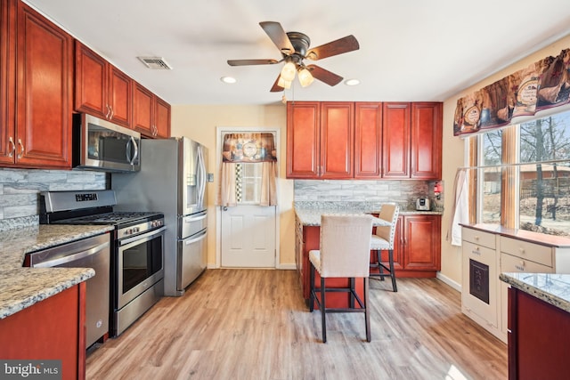 kitchen with light wood-style flooring, visible vents, appliances with stainless steel finishes, and reddish brown cabinets