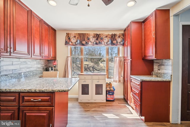 kitchen featuring reddish brown cabinets, tasteful backsplash, a ceiling fan, and light wood finished floors