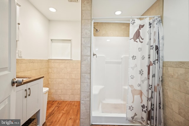 bathroom featuring tile walls, a shower with shower curtain, and wood finished floors