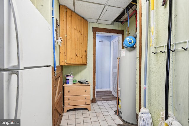 kitchen with light tile patterned flooring, a drop ceiling, gas water heater, and freestanding refrigerator