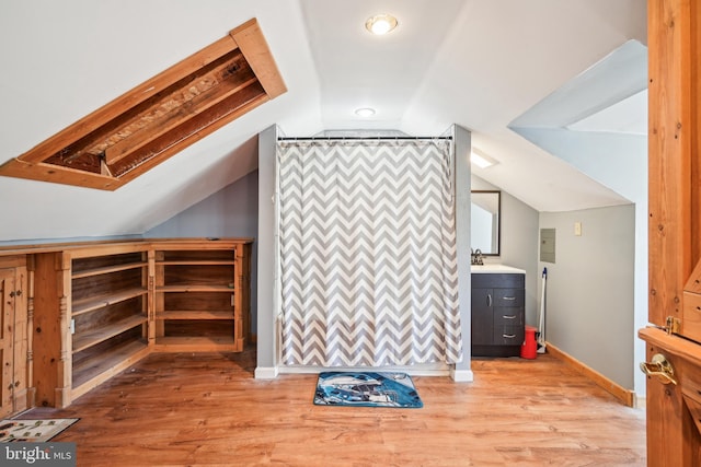 additional living space with an accent wall, lofted ceiling, light wood-style flooring, and baseboards