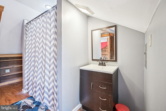 full bathroom featuring curtained shower, lofted ceiling, wood finished floors, and vanity